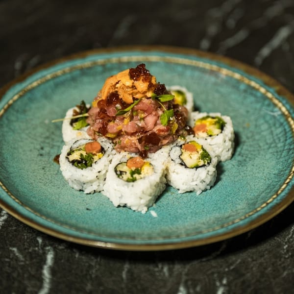 Sushi rolls with tuna tartare and sea urchin on a blue plate.