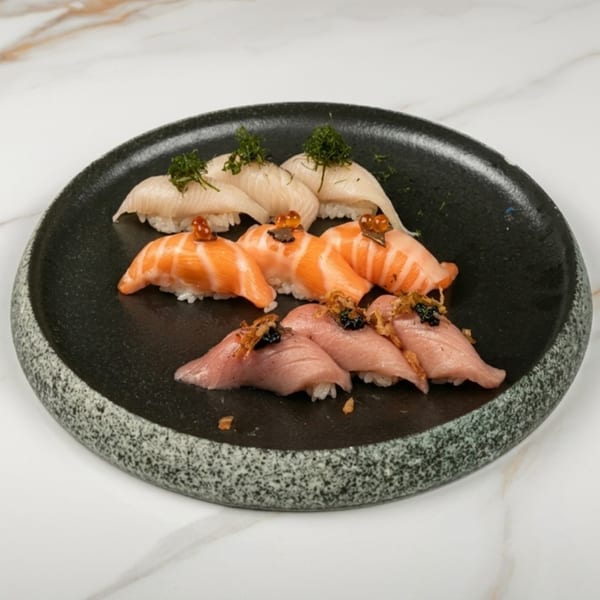 Assortment of sushi nigiri with various fish toppings and garnishes on a dark stone plate.